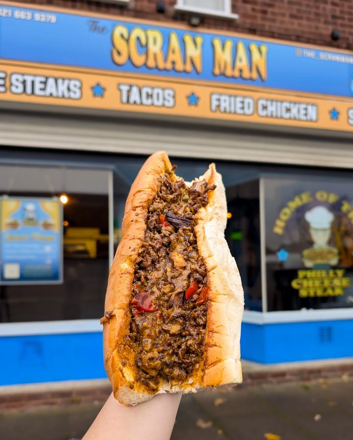 A cheesesteak held up outside The Scran Man shop